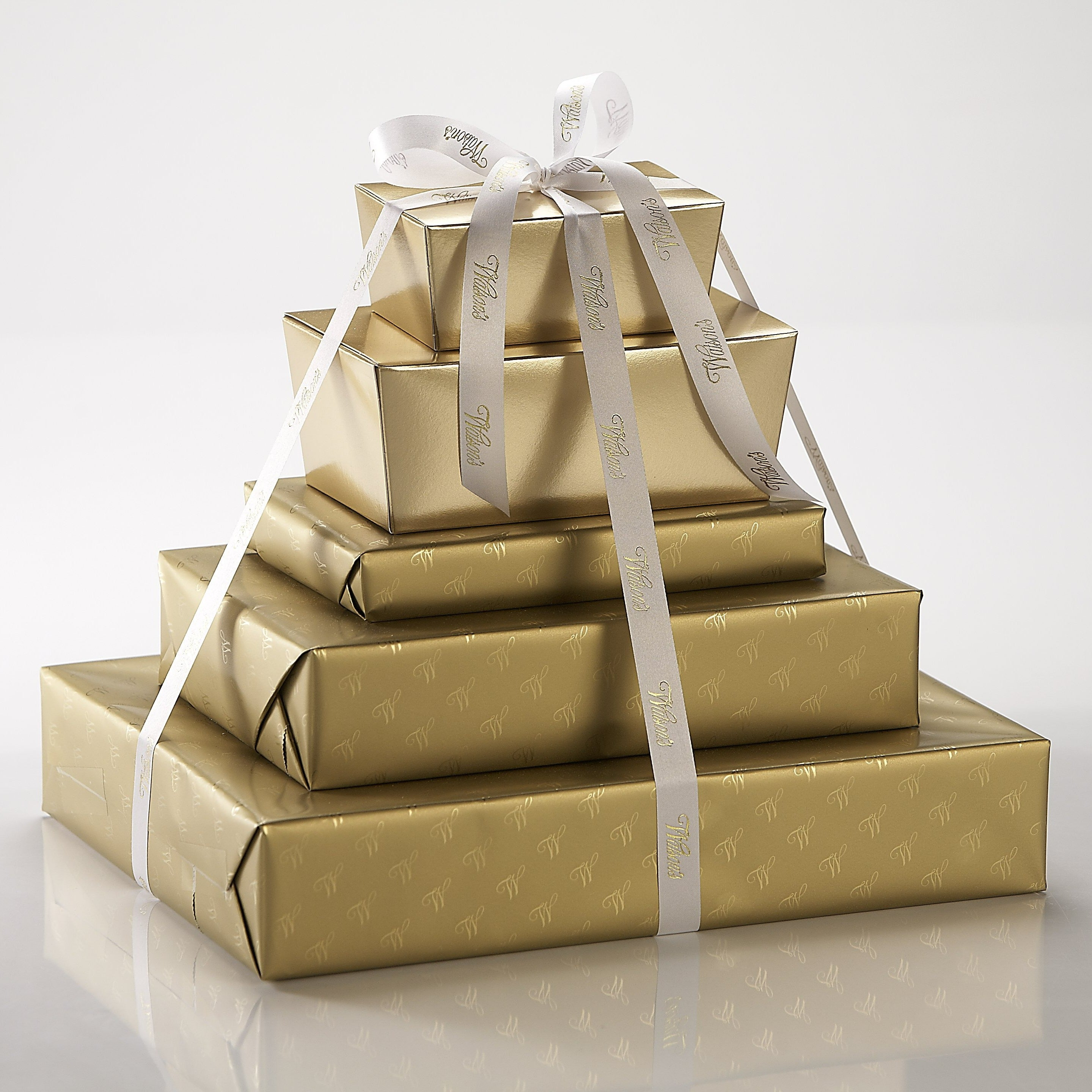 5 gold chocolate boxes stacked up on top of each other with a ribbon tying it together.